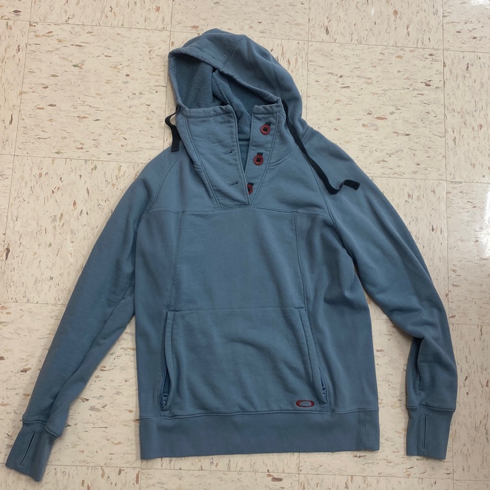 Oakley hoodie with button-collar detail, zippered front pocket, and thumb-holes